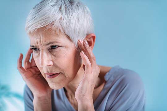 Woman holding her ears trying to stop the ringing. 